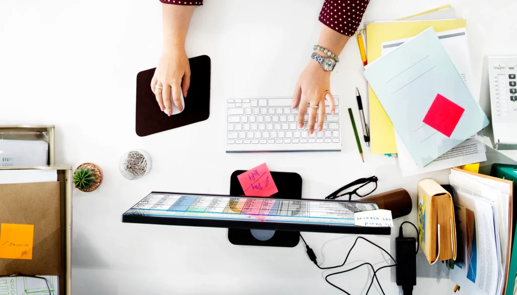 vue aérienne des mains travaillant sur ordinateur sur une table blanche au bureau