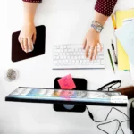 vue aérienne des mains travaillant sur ordinateur sur une table blanche au bureau
